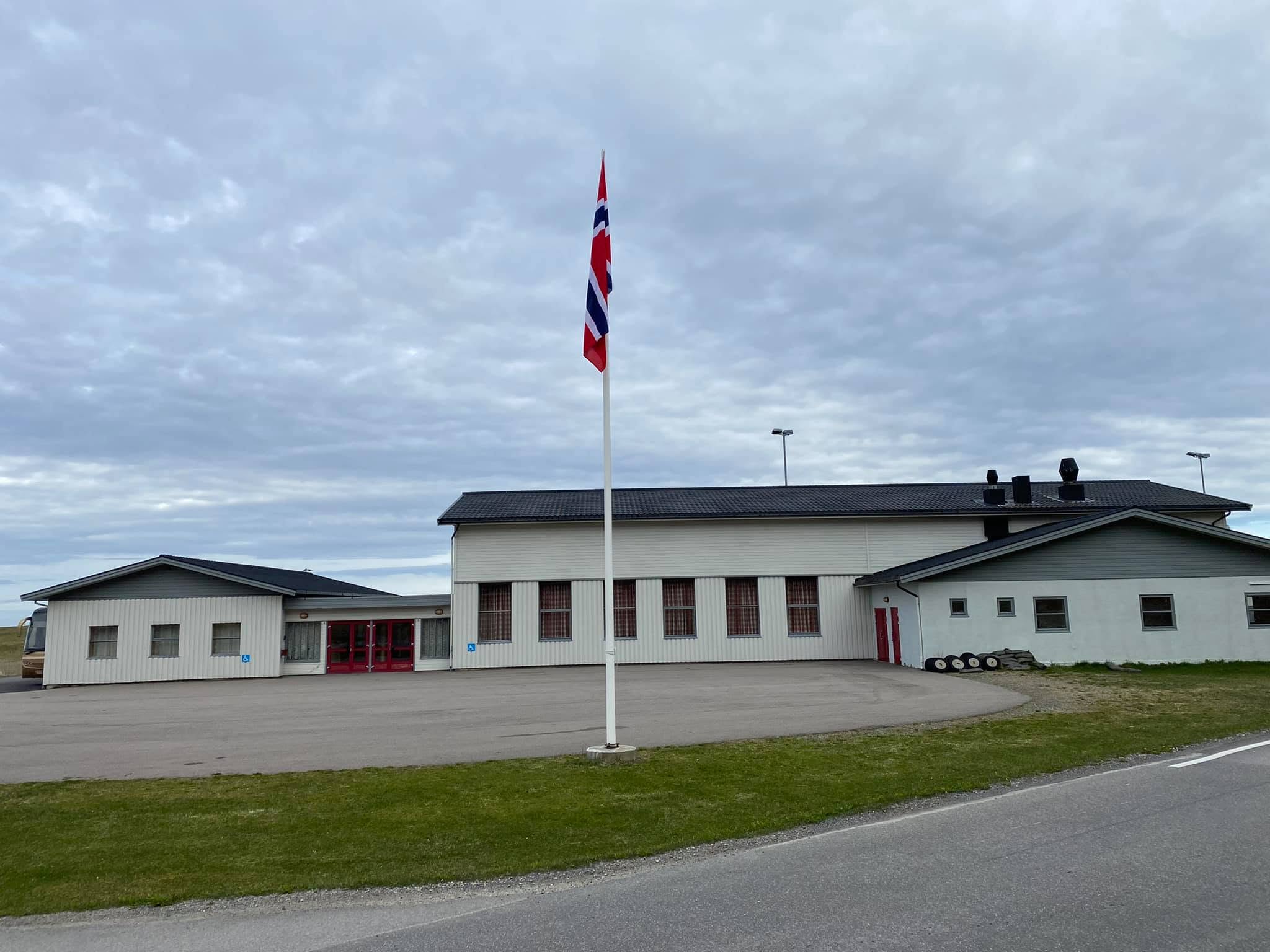 Bleik Samfunnshus sett fra parkeringsplassen, med inngang og flaggstang