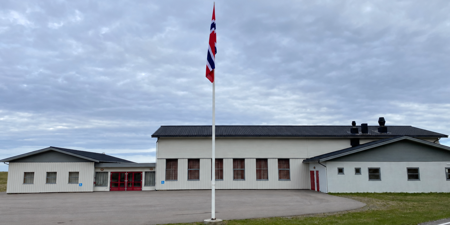 Fronten av Bleik Samfunnshus med inngang, tre takformer og flaggstang